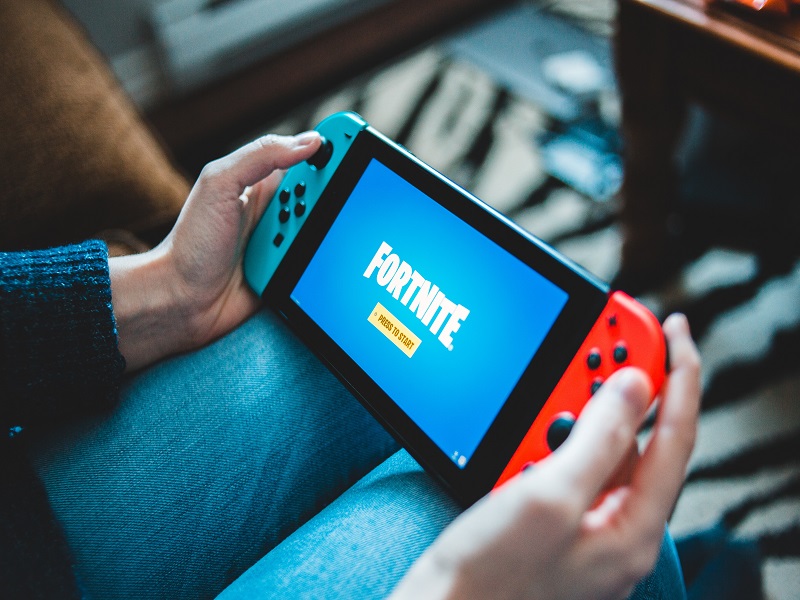 A woman holding a Nintendo switch on her lap playing Fortnite