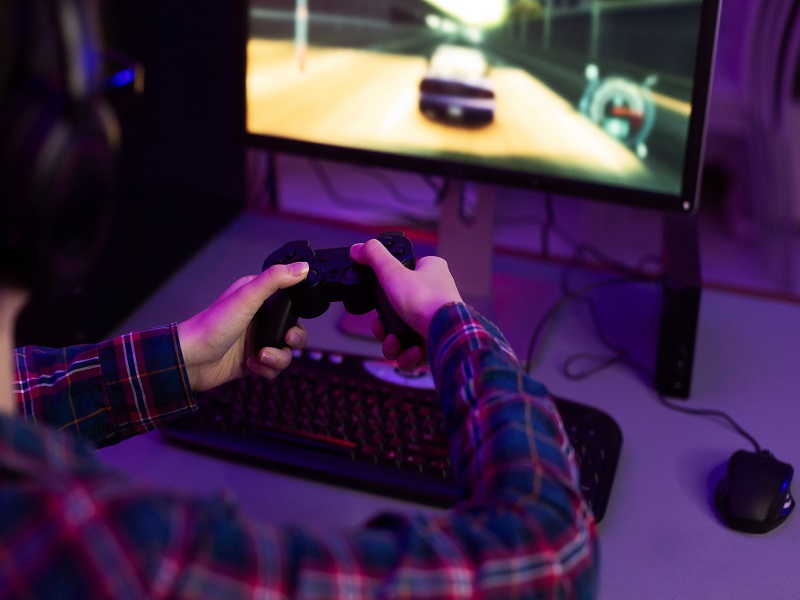 Female gamer playing video game with joystick, playing racing game