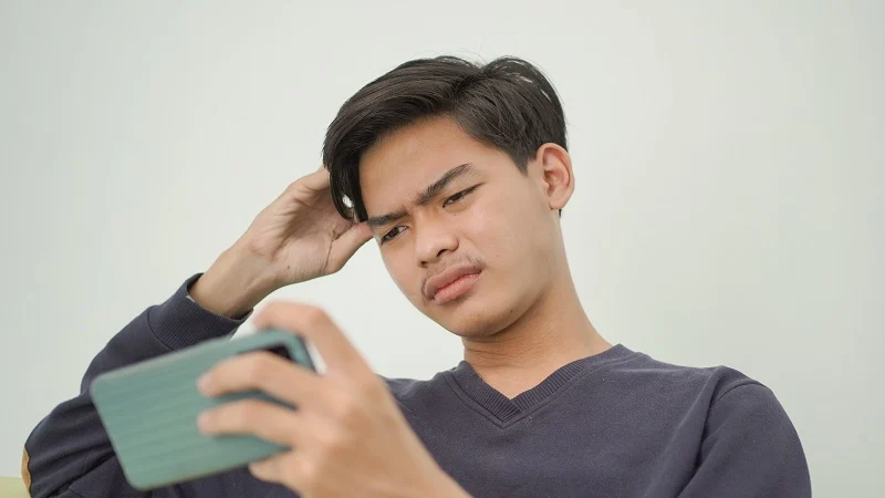 man looking at phone confused